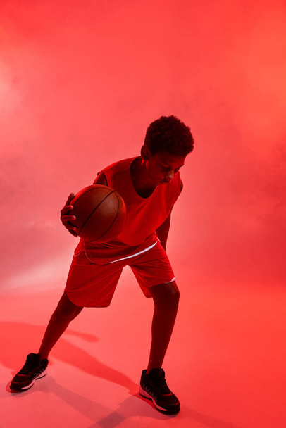Focused black boy playing basketball with ball - 写真・画像