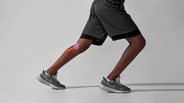 Side of run black boy with plasters on injured leg - Фото, зображення