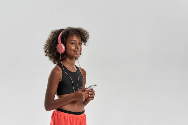Black girl listen music in earphones on smartphone - Fotó, kép