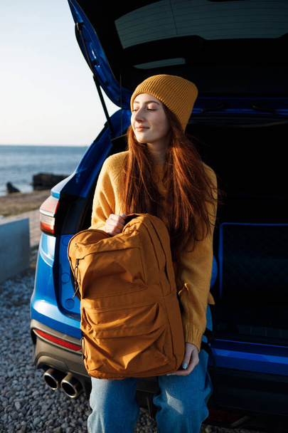 cute casual woman with red hair ready for travel by car - Фото, изображение