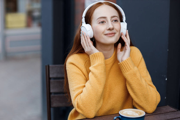 cute woman with headphones in cafe outdoor - Foto, afbeelding