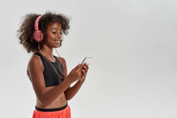 Sports black girl wear earphones browse smartphone - Foto, Imagem