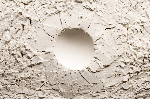 Cráter redondo sobre fondo blanco con grieta. Fondo agrietado con un agujero redondo. - Foto, imagen