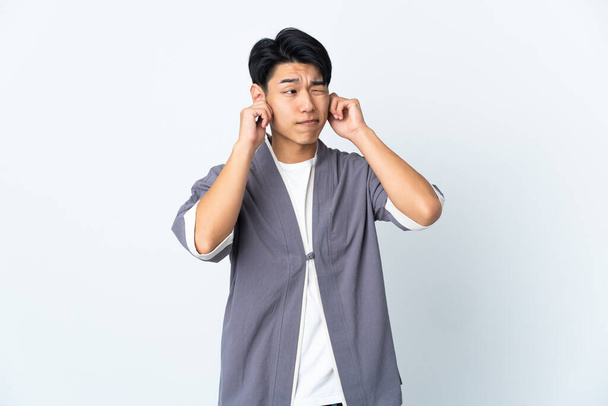 Jovem chinês isolado no fundo branco frustrado e cobrindo orelhas - Foto, Imagem
