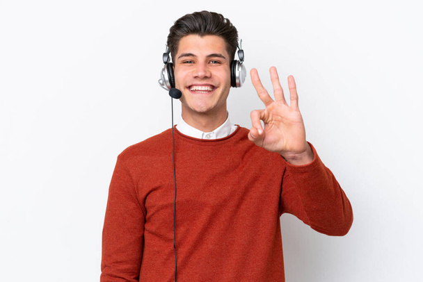 Telemarketer caucasian man working with a headset isolated on white background happy and counting three with fingers - Zdjęcie, obraz