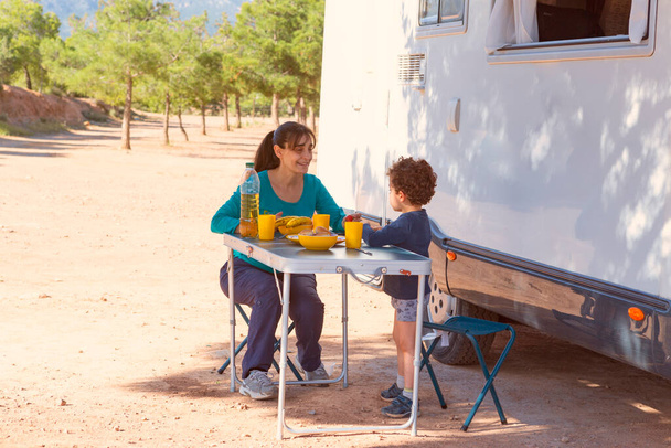 kind en moeder picknicken naast camper - Foto, afbeelding