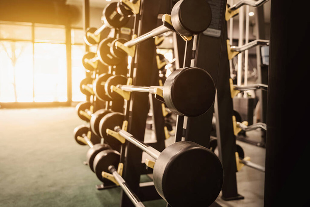 Close up row of barbells dumbbells in modern sports club with soft light. - Foto, Bild