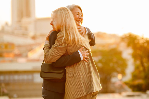 Mature multiracial businesswomen laughing and hugging during meeting outdoors - Foto, Imagen