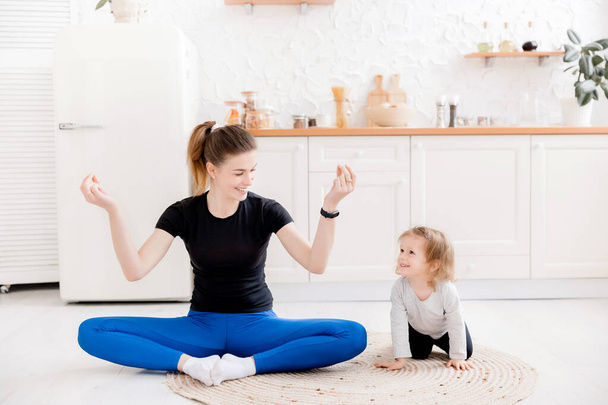 young mother and her daughter doing yoga exercises at home - Foto, imagen