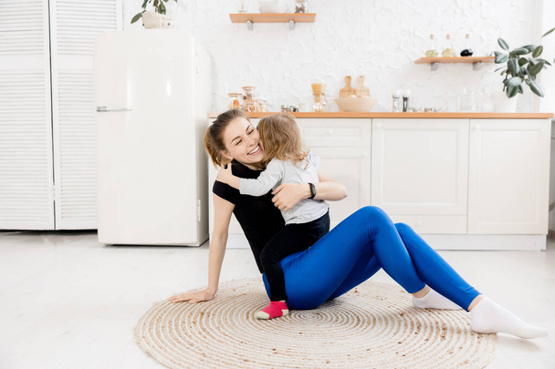 happy mother and daughter sitting on the floor and hugging - Photo, image