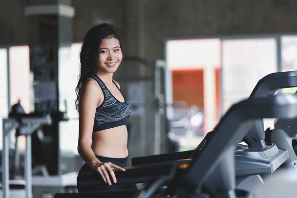 Ázsiai sportnő futópadon fut a fitness klubban. Kardio edzés. Egészséges életmód, edzőtermi edzés. Sportfutás koncepciója - Fotó, kép