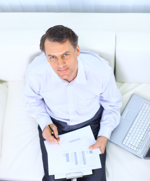 Senior businessman sitting on sofa and using laptop - Photo, Image