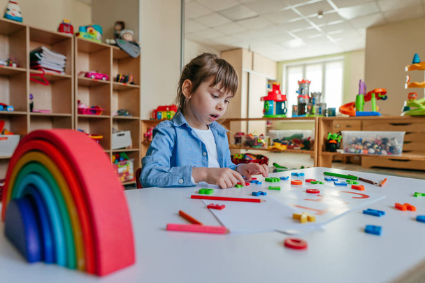 Little girl playing with colorful plastic letters at kindergarten or primary school. Tactile and sensory methods for learning. Education concept. - Foto, afbeelding
