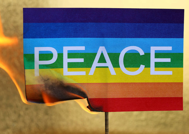 flag with the text PEACE as it burns with Fire on golden background - Foto, immagini