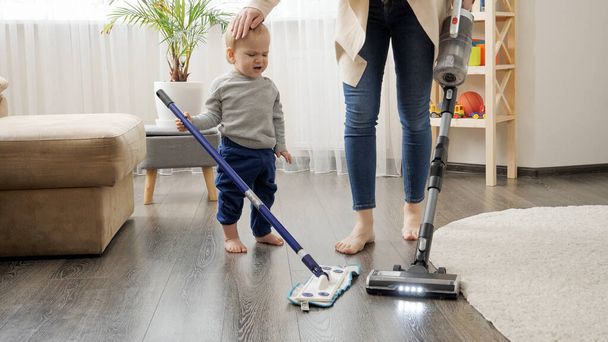 Pikkupoika auttaa äitiään siivoamaan kotona. - Valokuva, kuva