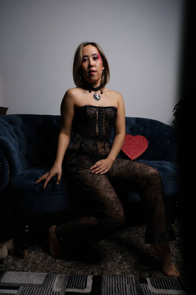 Photo shoot of a beautiful Vietnamese model on a sofa, with red heart and black lace outfit - Valokuva, kuva