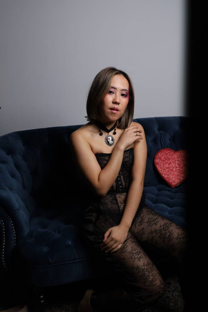 Photo shoot of a beautiful Vietnamese model on a sofa, with red heart and black lace outfit - Zdjęcie, obraz