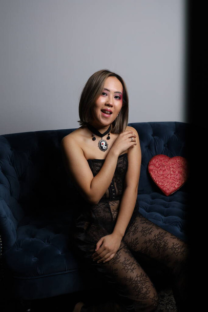 Photo shoot of a beautiful Vietnamese model on a sofa, with red heart and black lace outfit - 写真・画像