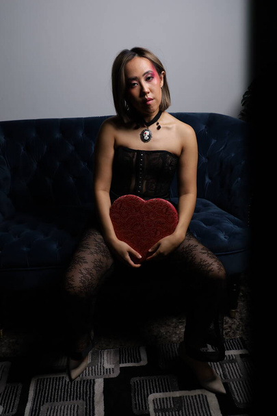 Photo shoot of a beautiful Vietnamese model on a sofa, with red heart and black lace outfit - Fotoğraf, Görsel
