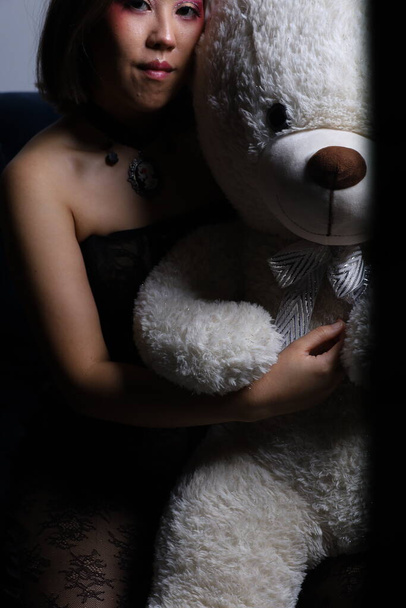 Photo shoot of a beautiful Vietnamese model on a couch with a teddy bear - Foto, Imagem
