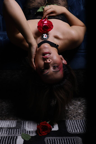 Photo shoot of a beautiful Vietnamese model holding a rose, and sitting on a couch - Foto, Bild