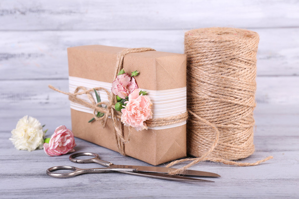 Beautiful gift with flowers and decorative rope, on old wooden background - Photo, Image