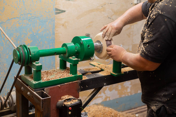 Closeup of person sanding wooden product using sandpaper on a lathe - Photo, image