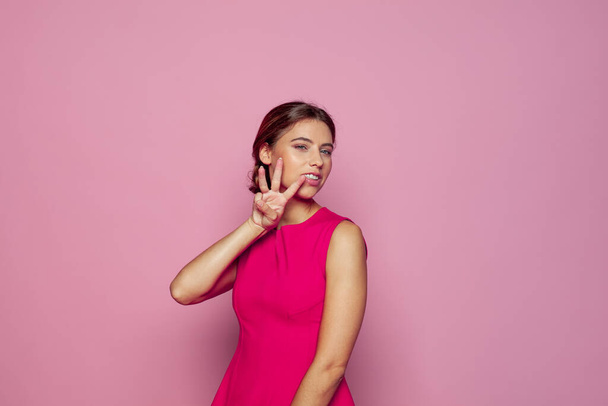 Mujer joven contando y mostrando tres con los dedos sobre fondo rosa - Foto, imagen