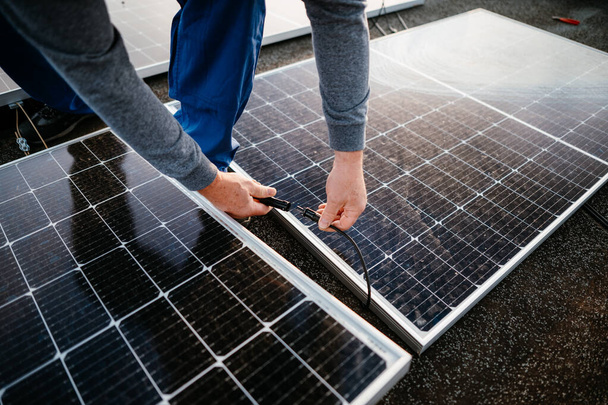 İşçi güneş enerjisi panelleri kuruyor. İki paneli birbirine bağlayın. eko kavramı - Fotoğraf, Görsel
