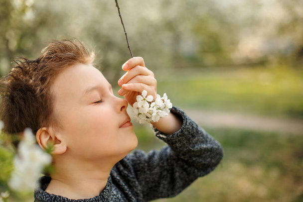 Štěstí a rozrušené dítě si užívá jarní den. Rozkošný chlapec v jarní kvetoucí zahradě. Mezinárodní den dětí. Chlapec může dýchat bez alergie. Osoba zavřené oči a dýchání.  - Fotografie, Obrázek
