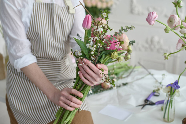 Young creative woman in a flower shop, with a bouquet in her hands. A startup of florist business. - Foto, afbeelding