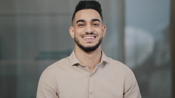 Vrolijke jonge man hispanic knappe man met tanden glimlach kijken naar camera mannelijk gezicht portret zakenman glimlachen arabisch professioneel manager ondernemer poseren positief in modern kantoor close-up uitzicht - Video