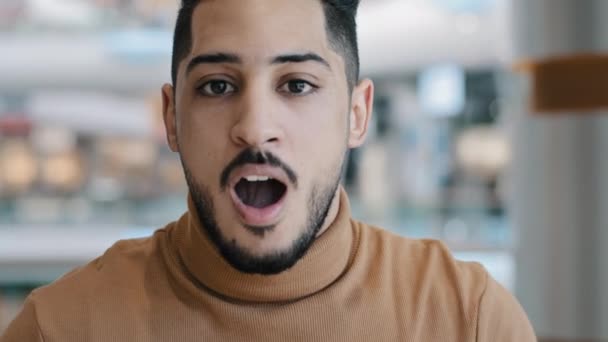 Portrait emotional excited young arab guy opens mouth in amazement astonishment surprise feels shock expressing disbelief looking at camera disapprovingly shaking finger showing discontent gesture - Footage, Video