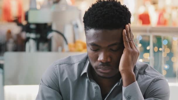 Zbliżenie młody niezdrowy zmęczony Afrykanin amerykański człowiek czuje ból głowy ciśnienie trzymając się za ręce na głowie cierpiących na przewlekłą migrenę doświadcza silne bolesne uczucie niepokojący niepokój stres - Materiał filmowy, wideo