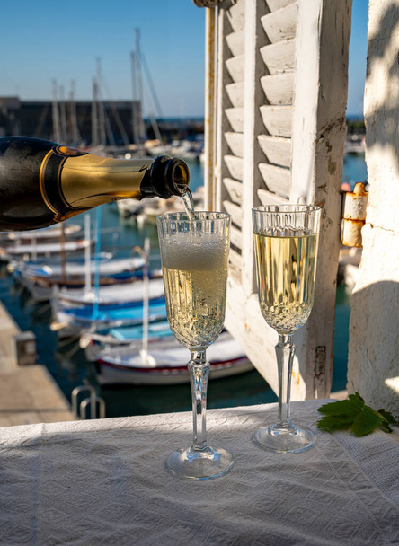 Celebração de aniversário no verão com dois copos de vinho espumante de champanhe francês e vista sobre barcos de pescadores coloridos no antigo porto em Cassis, Provence, França - Foto, Imagem