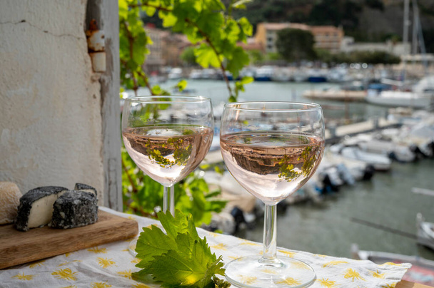 Provenzalischer Wein in Gläsern, serviert auf einer Außenterrasse mit Blick auf den alten Fischerhafen mit bunten Booten in Cassis, Provence, Frankreich - Foto, Bild