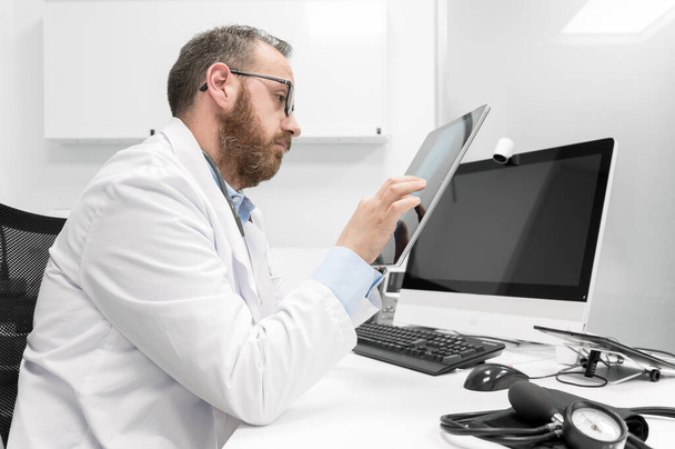 Doctor using his tablet computer at work - Fotó, kép