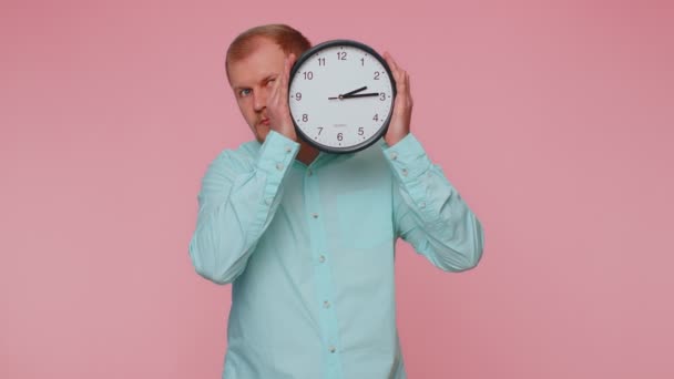Jeune homme tenant montre horloge, se cachant, vérifiant l'heure sur horloge, courant tard au travail étant en retard - Séquence, vidéo
