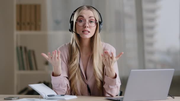 Woman helpline manager consultant adviser instructor distant teacher coach in headphones speaks showing gestures in air explaining online briefing guide video call conference help remotely e-learning - Imágenes, Vídeo
