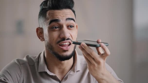 Arab millenniumi üzletember vállalkozó ül a munkahelyen beszélni kihangosító barátjával, hogy hangfelismerés használata virtuális asszisztens digitális alkalmazás rekord audio üzenet mobil app - Felvétel, videó