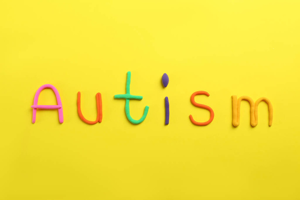 Word Autism made with colorful plasticine on yellow background, flat lay - Foto, Imagen