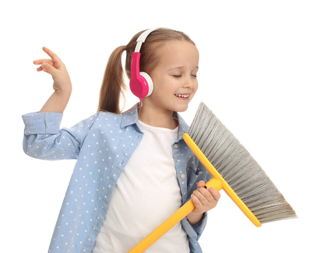 Cute little girl in headphones with broom singing on white background - Фото, изображение