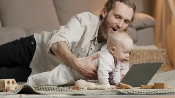 Felnőtt kaukázusi apa szakállas egyedülálló apa újszülött baba videohívás anya vagy rokonok beltéri apa csecsemő baba integető kezét üdvözlő hello beszélgetés online konferencia távoli chat - Felvétel, videó
