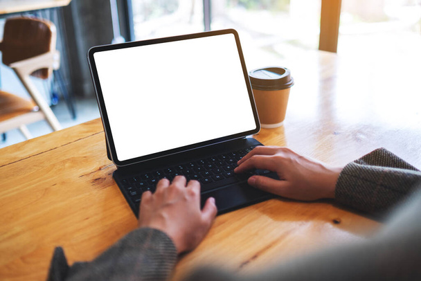 Mockup obrázek rukou pomocí a psaní na klávesnici tabletu s prázdnou bílou plochu obrazovky jako počítač PC na stole - Fotografie, Obrázek