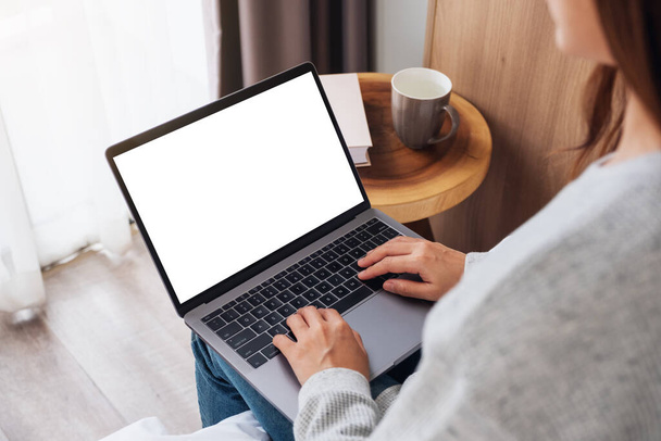 Attrappe einer Frau, die am Laptop mit leerem Bildschirm arbeitet und tippt, während sie zu Hause im Bett sitzt - Foto, Bild