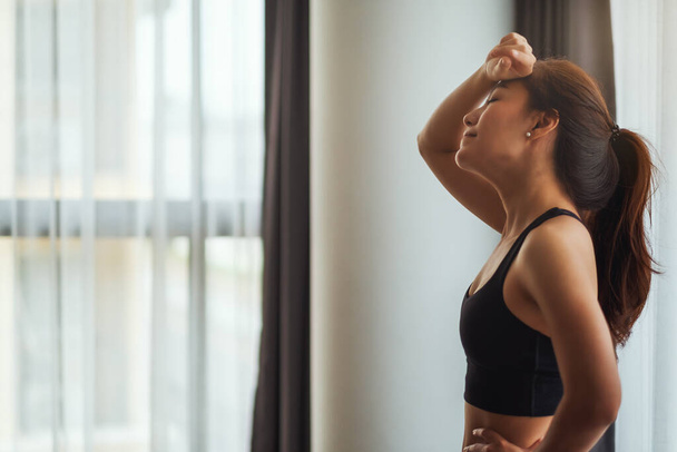 Closeup image of a tired young asian woman resting after workout at home - Valokuva, kuva