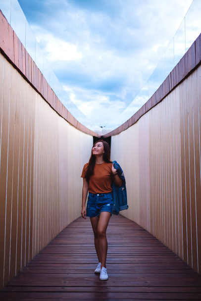 A young asian woman traveling and walking into a modern wooden building - Zdjęcie, obraz
