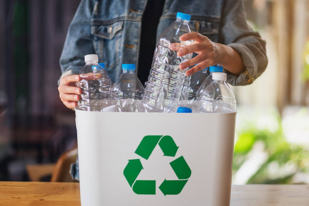 Женщина, собирающая и разделяющая переработанные пластиковые бутылки для мусора в мусорный бак дома - Фото, изображение