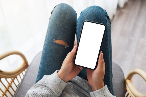 Mockup image of a woman holding mobile phone with blank desktop white screen while lying on a sofa at home - Foto, Imagen