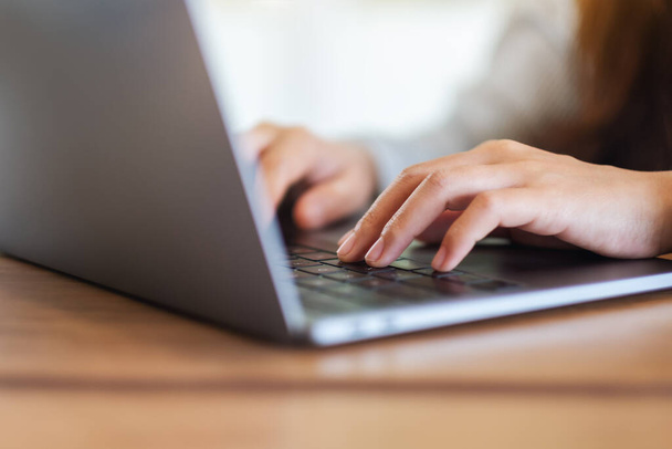 Zbliżenie obrazu kobiety pracującej i wpisującej na laptopie klawiaturę komputera na drewnianym stole - Zdjęcie, obraz